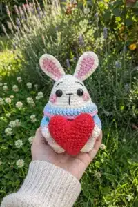 Bunny amigurumi free Valentine crochet pattern held in hand showing size of finished white bunny with red heart